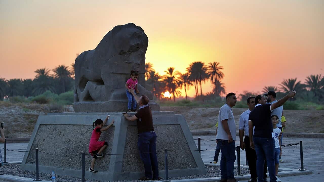 People stand near the Lion of Babylon at the archaeological site of Babylon, Iraq, Friday, July 5, 2019.