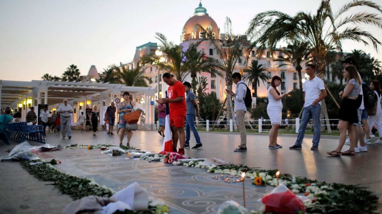 A man prays in front of flowers and candles placed in tribute of the victims of the 2016 Nice attack on the famed Boulevard des Anglais, in Nice, France
