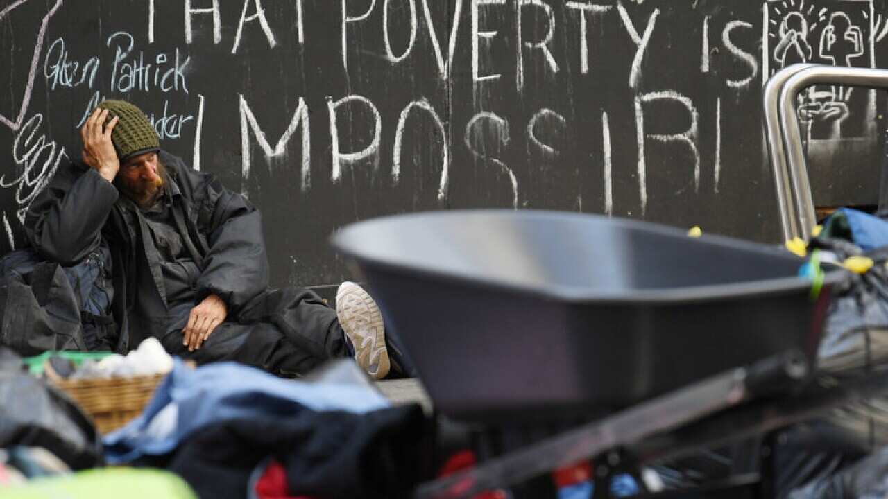 A homeless man sits on the ground as others pack away their belongings and prepare to leave Tent City in Martin Place in Sydney, Friday, August 11, 2017. (AAP Image/David Moir) NO ARCHIVING
