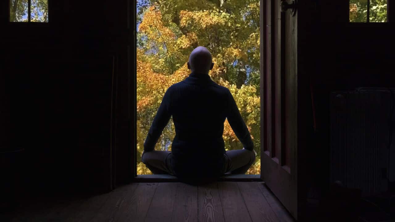 Man meditates in front of his house.