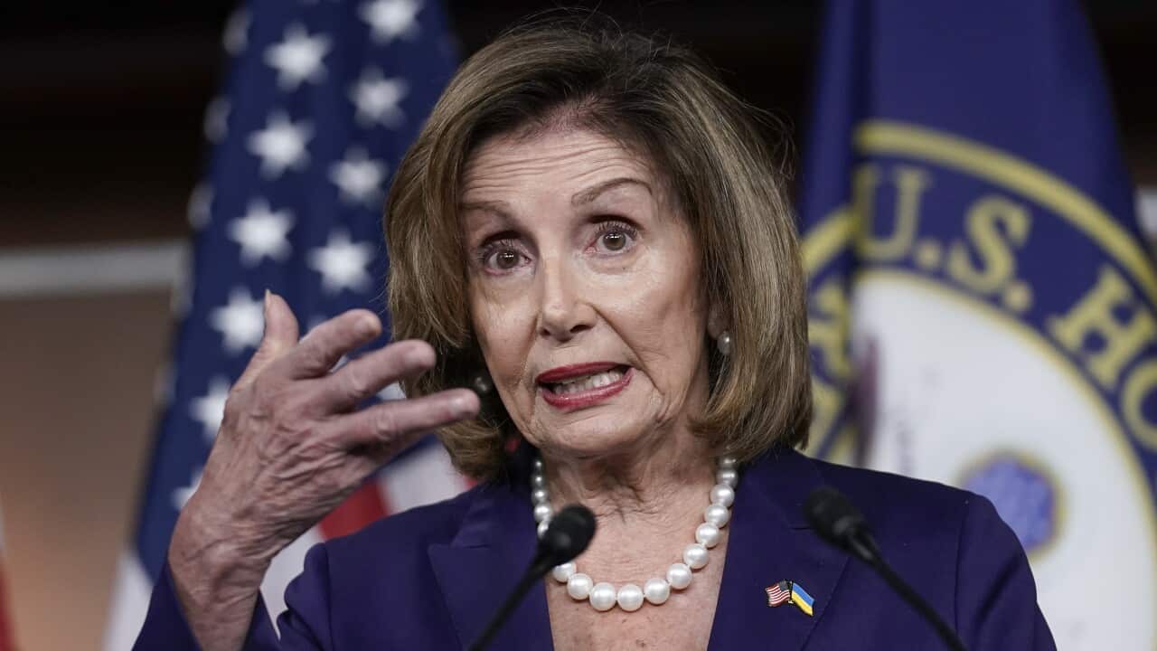Nancy Pelosi speaking to the camera with right arm raised