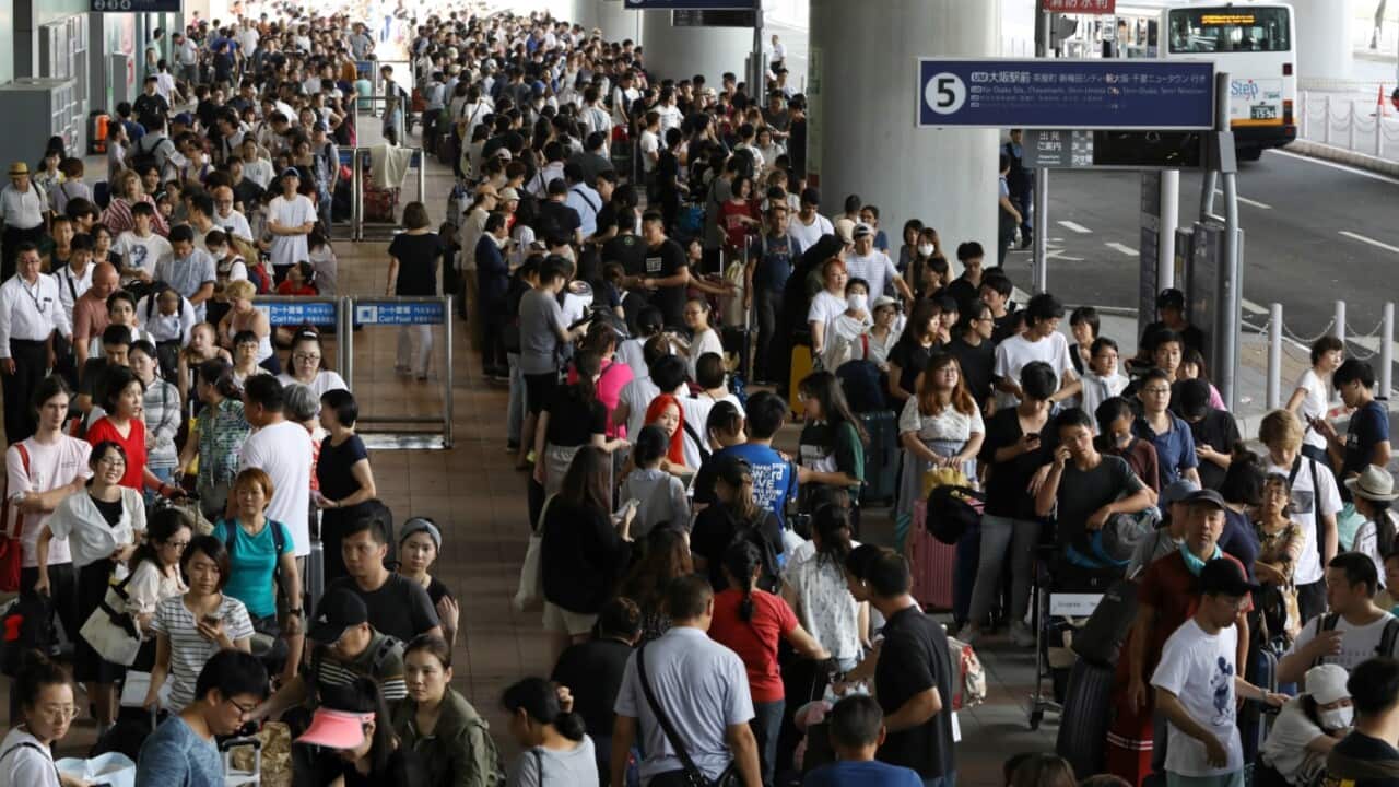 Passengers who stayed overnight make a long queue to wait for buses to be transported to a speed boat port, at Kansai International Airport in Izumisano