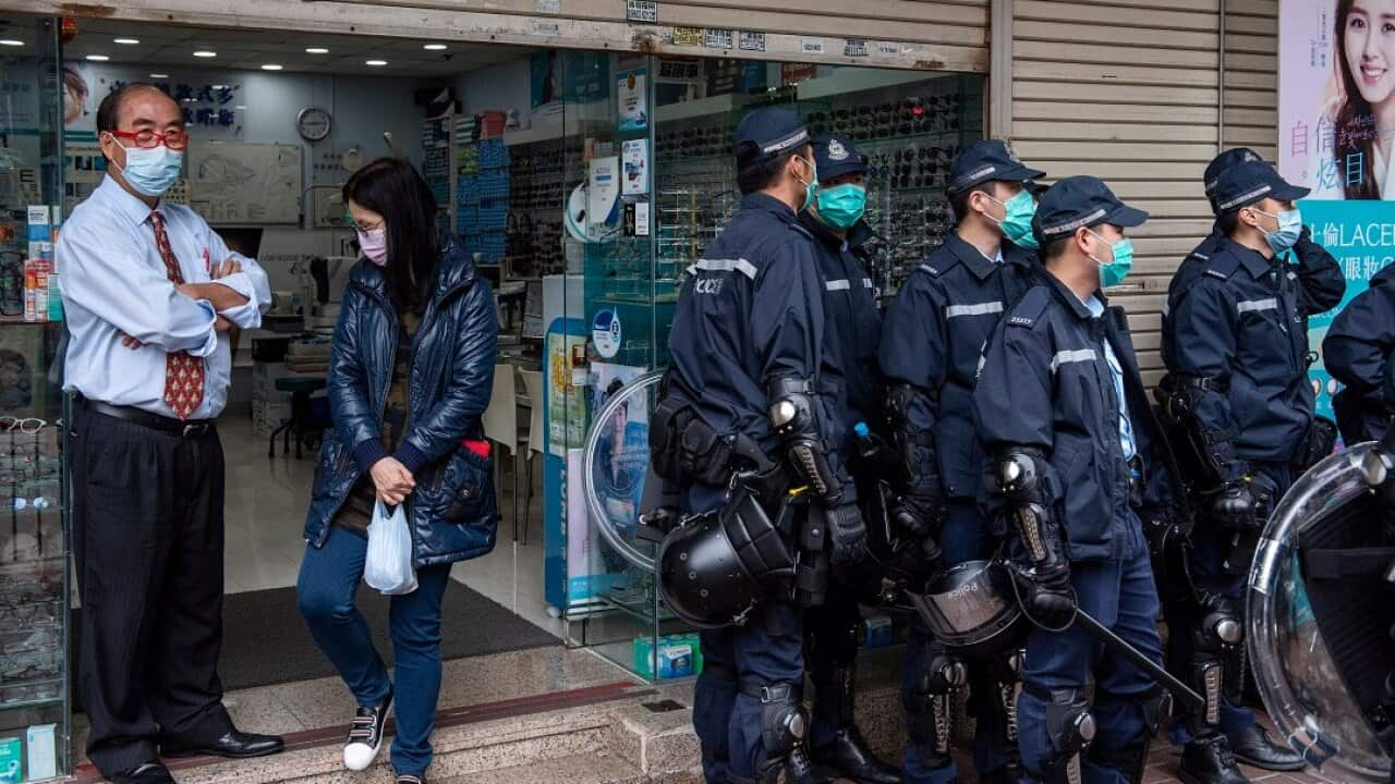 Optical store workers stand next to riot police officers during a protest against the use of a quarantine center in Cheung Sha Wan in Hong Kong. (Photo by Miguel Candela / SOPA Images/Sipa USA)