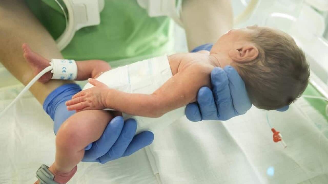 A nurse holds a newborn baby.