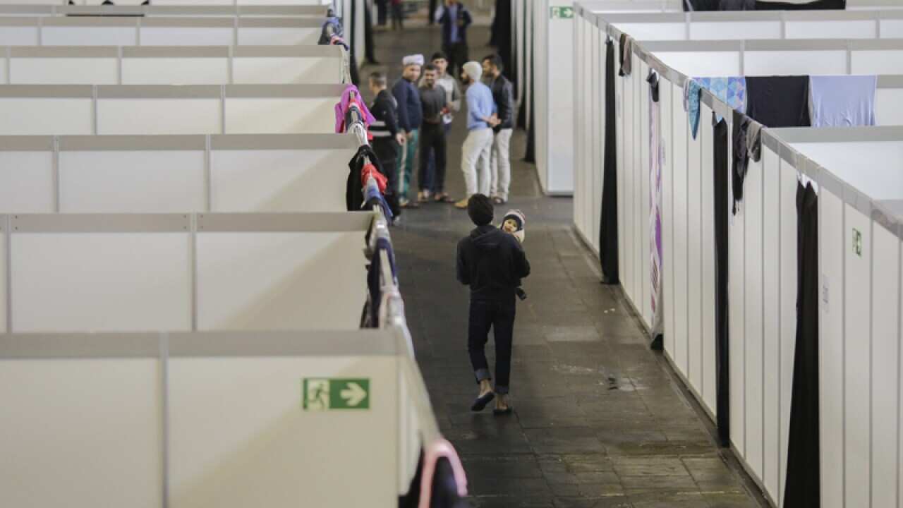 People walk through a temporary emergency shelter for migrants