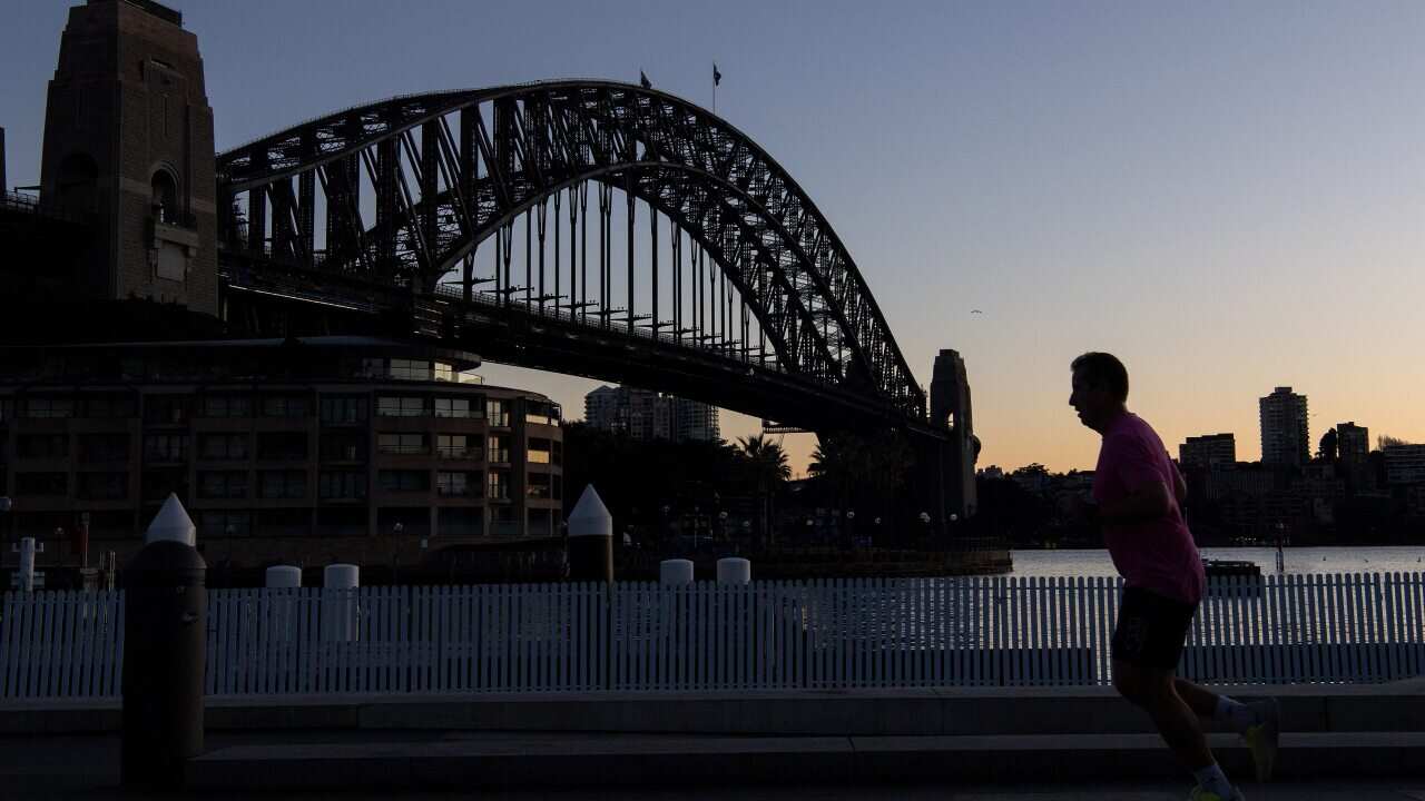 Members of the public exercise by the Sydney Harbour Bridge at sunrise in Sydney on 13 June 2022.