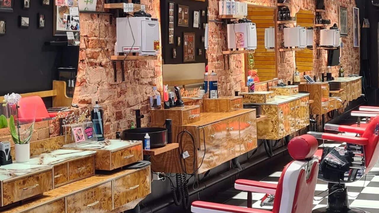 Three barber chairs facing mirrors, on a checkered floor.