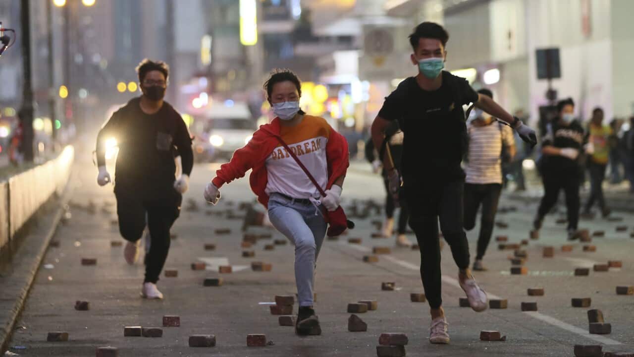 Anti-government protesters flee  on a street as riot police vehicle chases in Hong Kong on 19 November, 2019. 