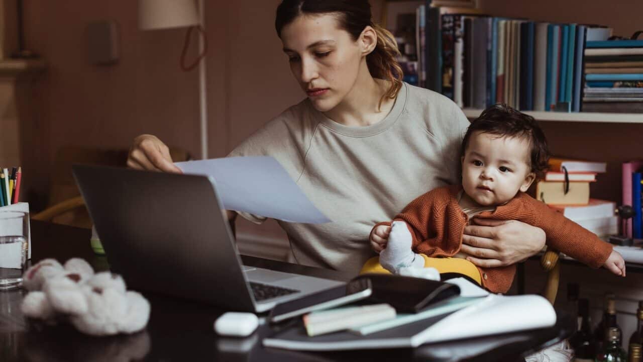 Female professional reading document while sitting with male toddler at home