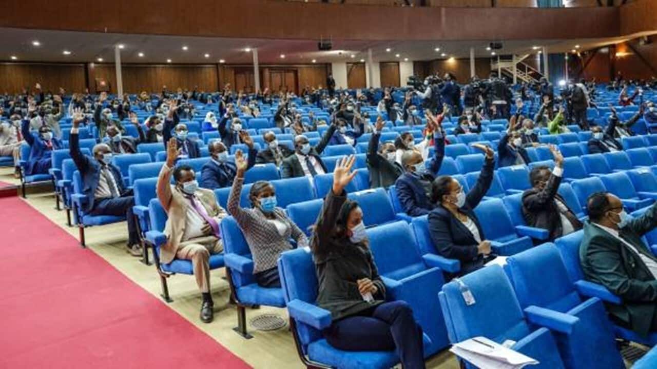Members of the Parliament raise their hands to vote.