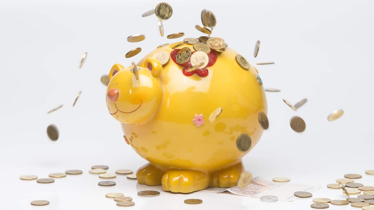 A yellow piggy bank with coins dropping on it