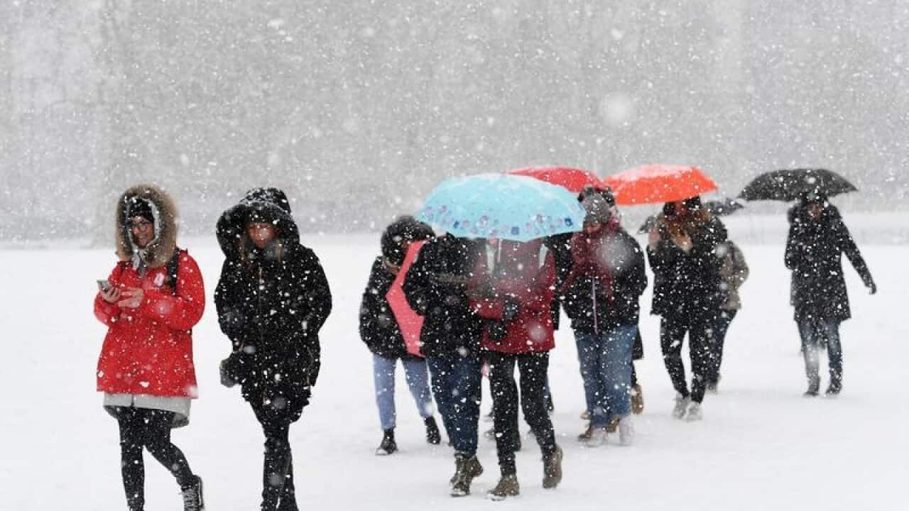 People walk through heavy snow in London's Green Park