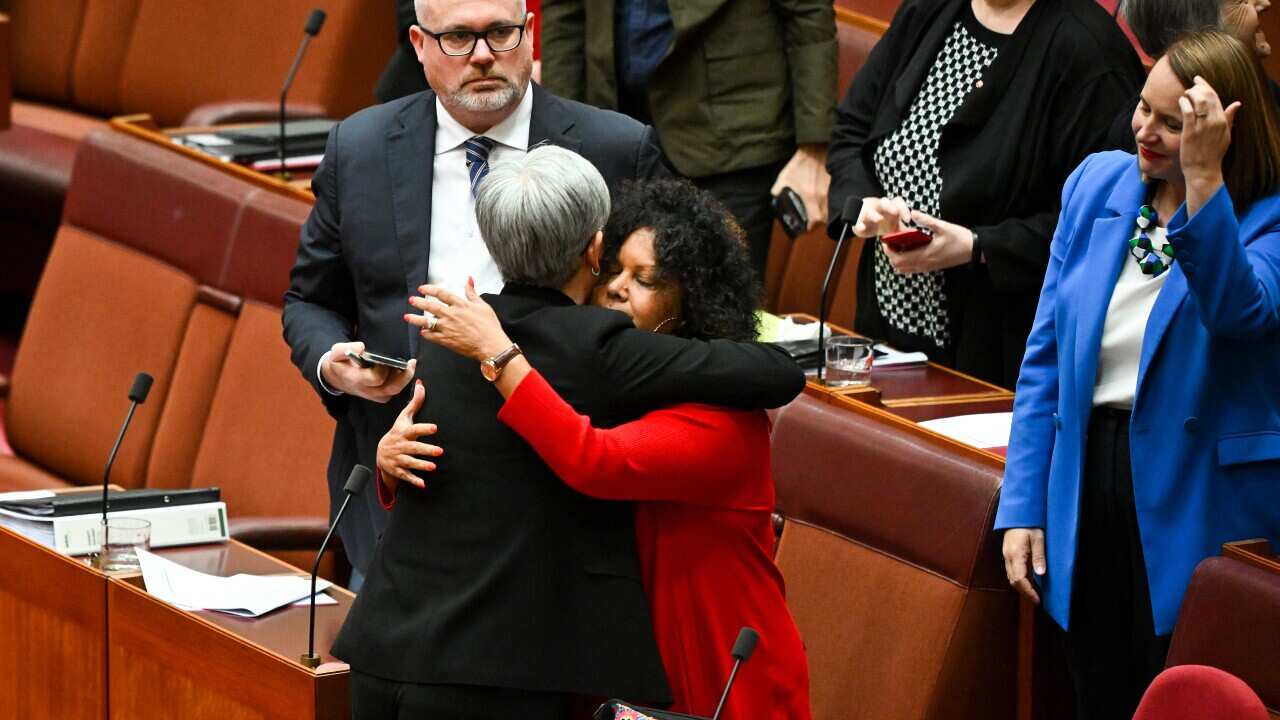 Two women embrace each other in parliament house.