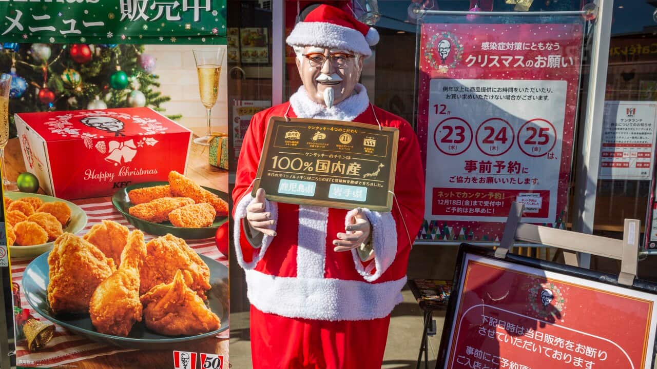 A poster of fried chicken next to a man in a red and white Santa suit holding a sign in Japanese