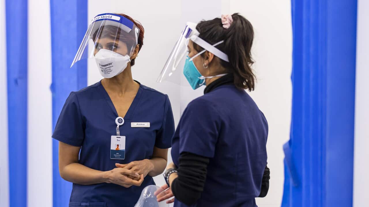 Health care workers at a COVID-19 vaccination hub in Melbourne, wearing face masks.