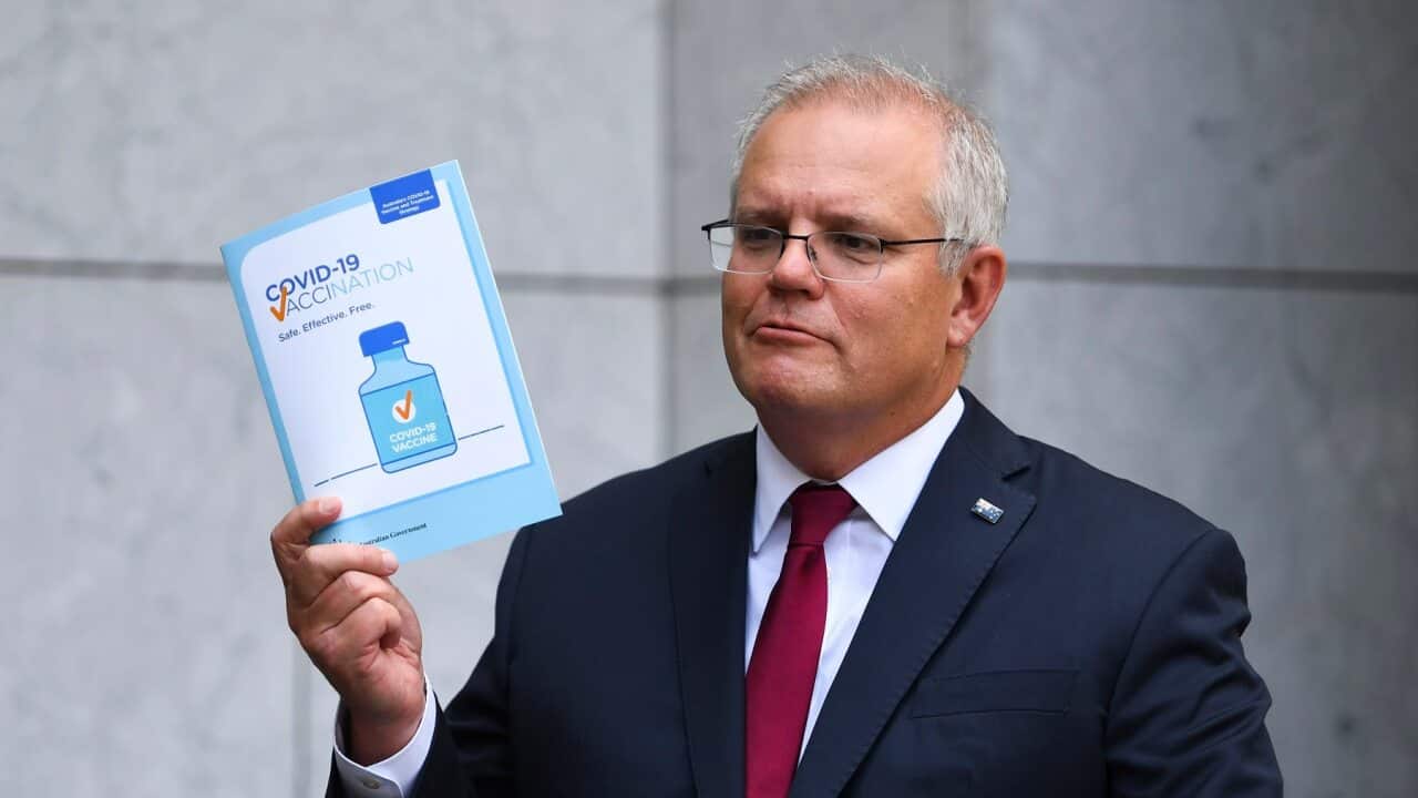 Scott Morrison holds up a COVID19 vaccination leaflet