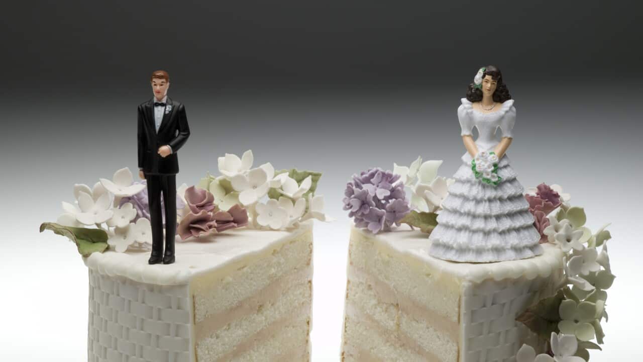 Bride and groom figurines standing on two separated slices of wedding cake