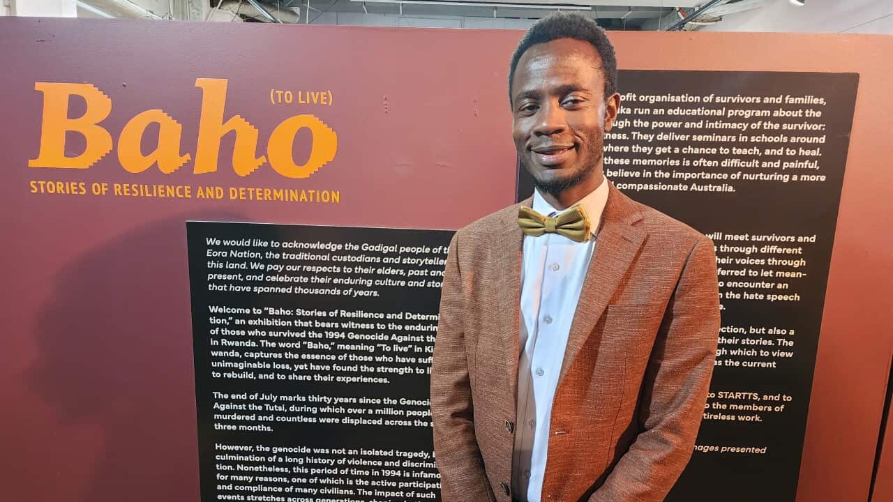 JP Amedee mbele ya bango la onesho lake la Baho (kuishi).