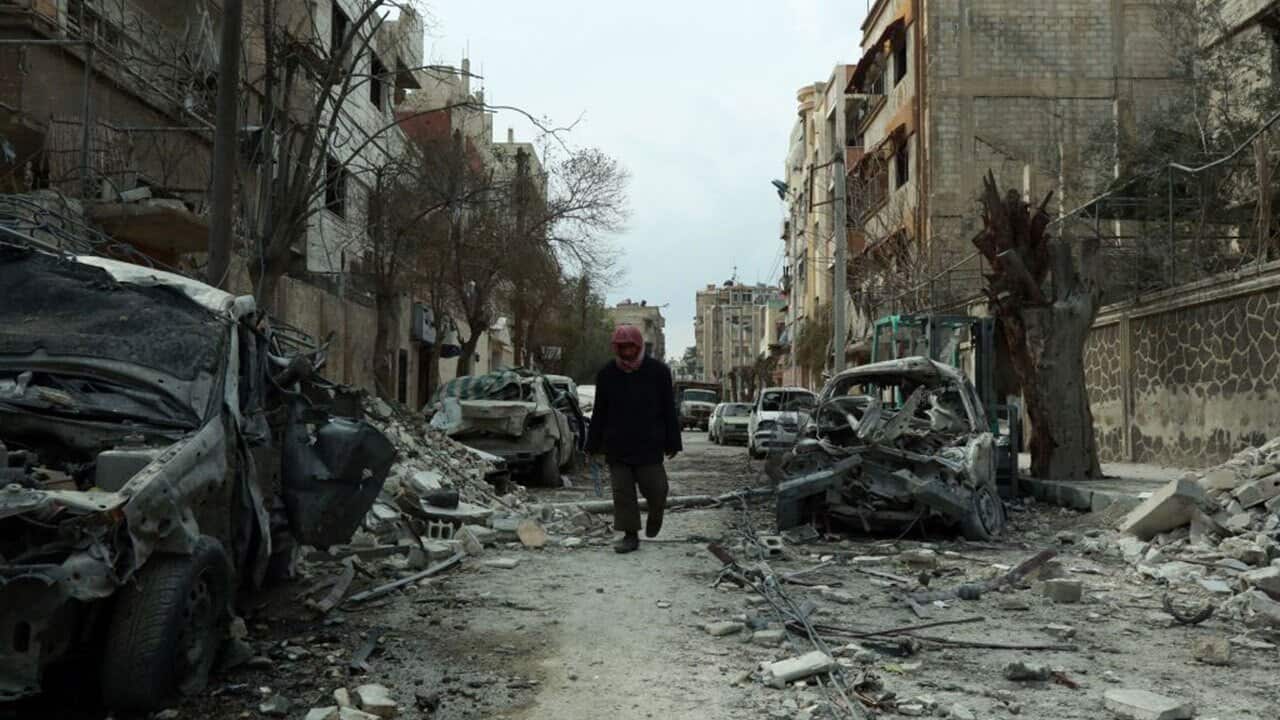 A Syrian man walking next to damaged buildings following regime air strikes in the Syrian rebel-held town of Douma, in the besieged Eastern Ghouta region.