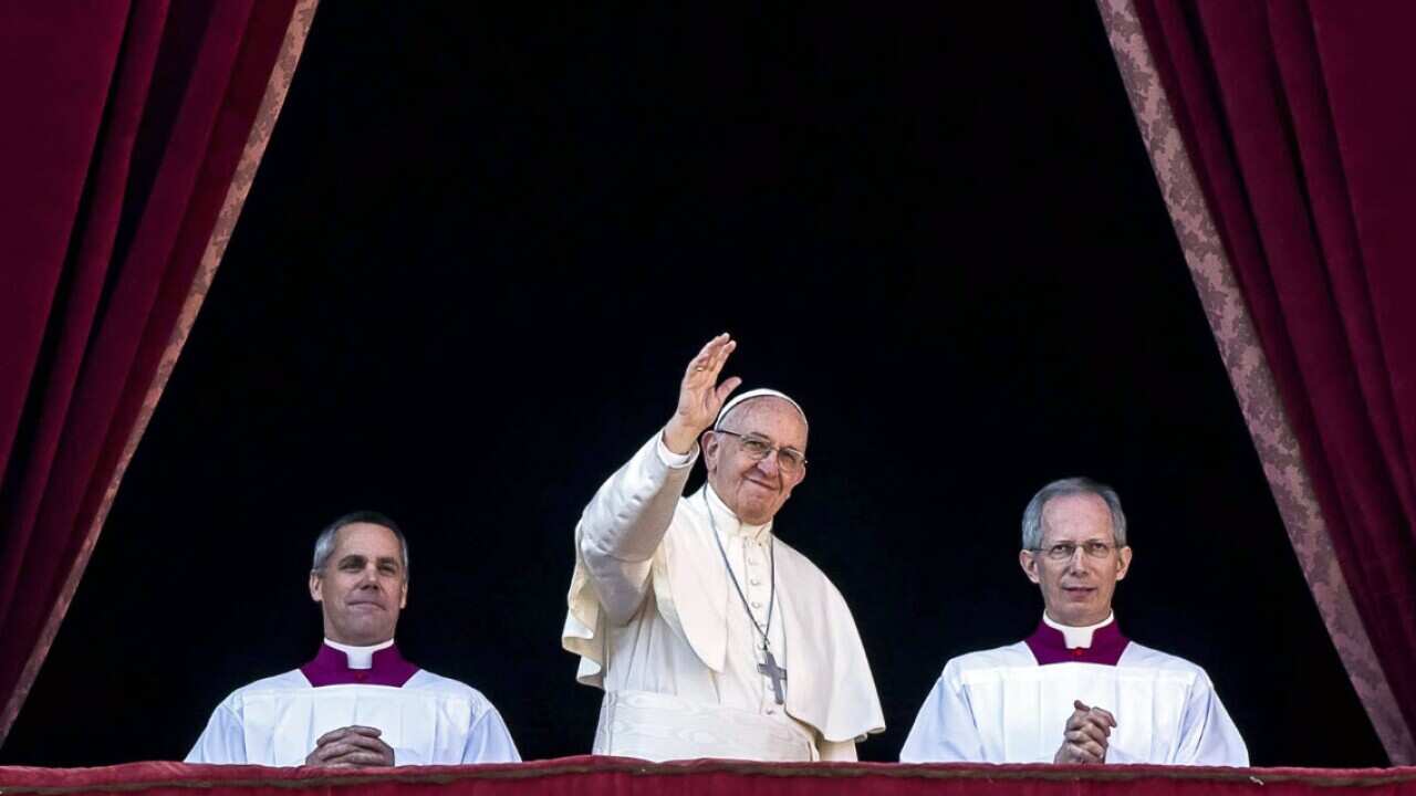 Pope Francis waves to the faithful as he delivers his Christmas Day message from the central balcony of St. Peter's Basilica at the Vatican.