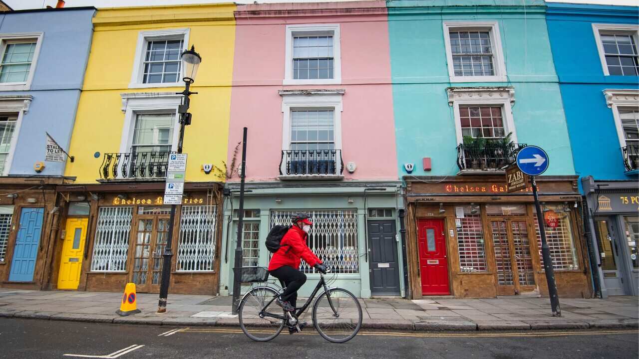 A cyclist wearing a face mask rides past closed up shops on Portobello Road in West London as the UK continues in lockdown.