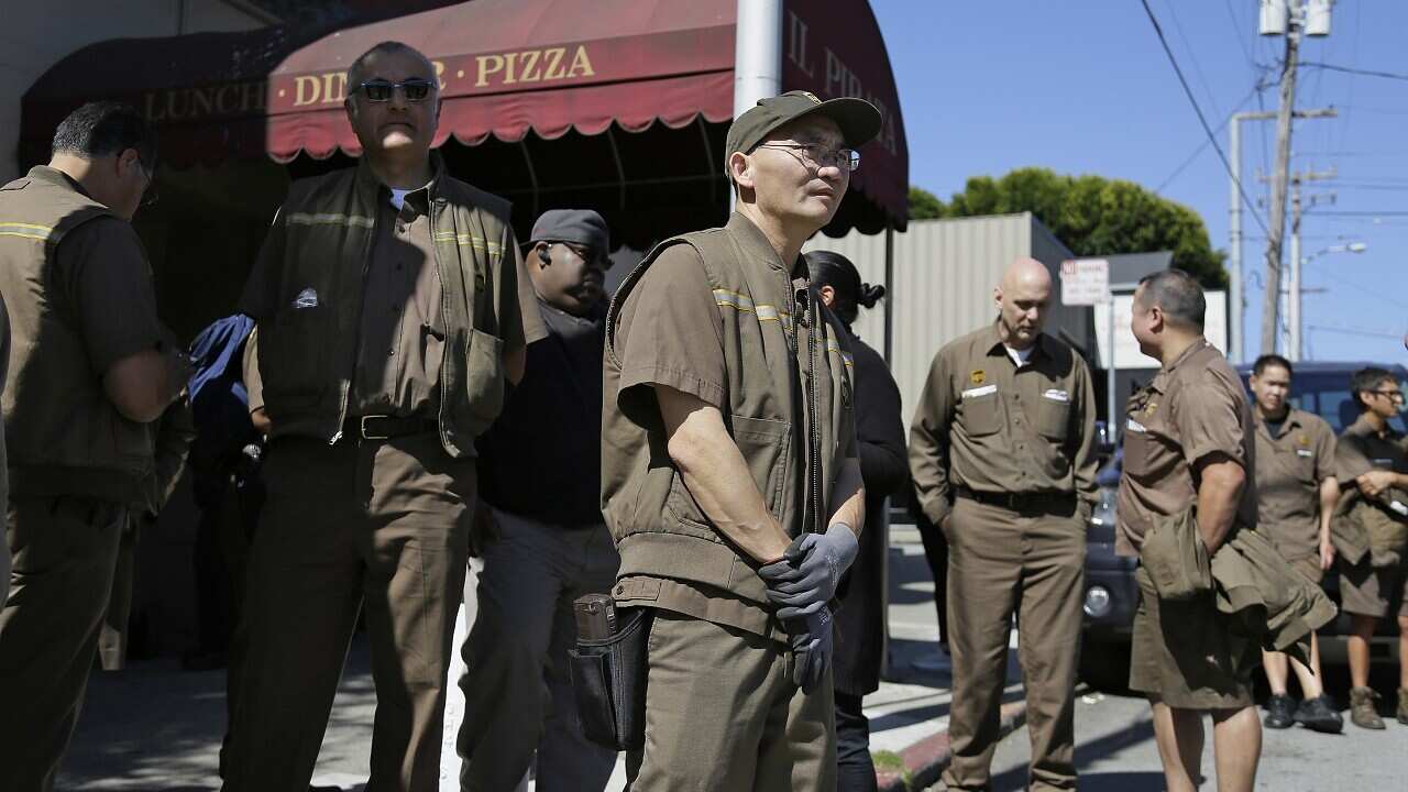 UPS workers gather outside a UPS package delivery warehouse where a shooting took place in San Francisco. 