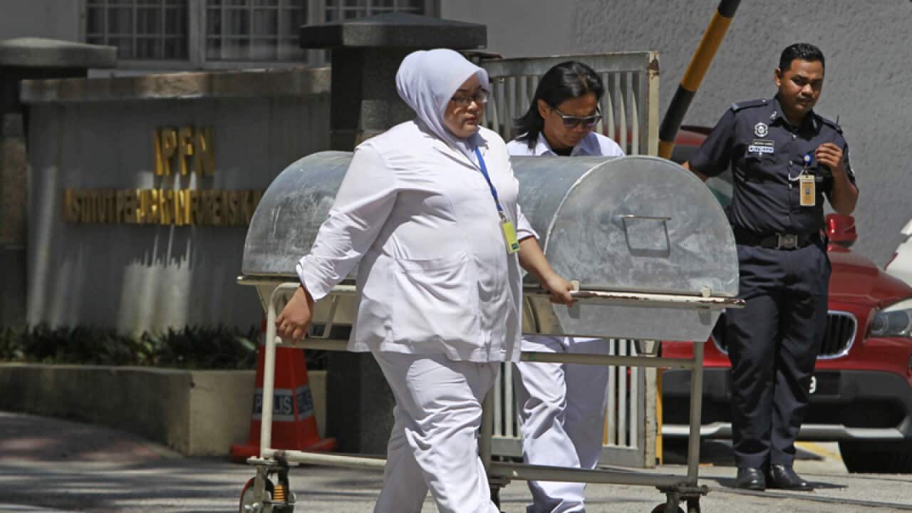 Medical staff wheel a casket trolley from the forensic department