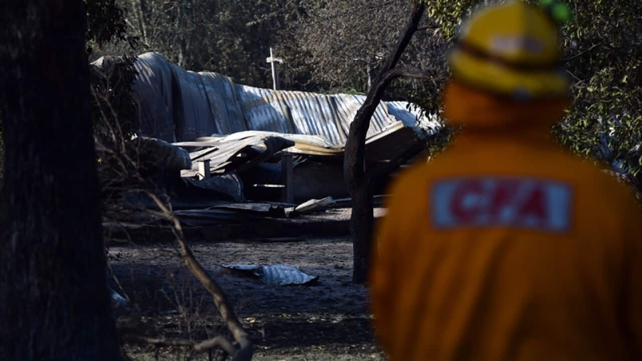 A CFA firefighter surveys the ruins of a house near Lancefield