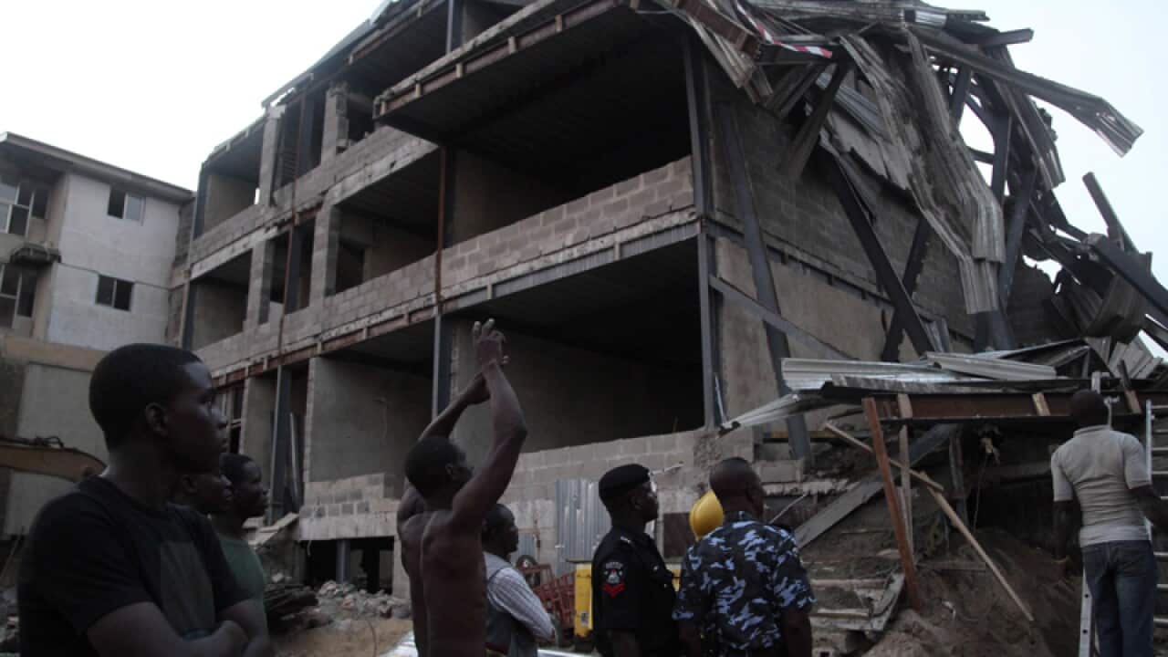 People gather near the site of a building collapse