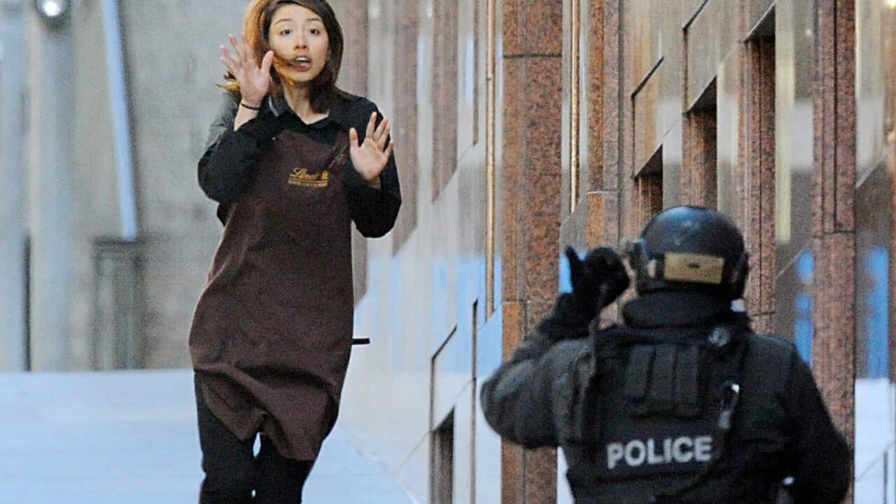 Elly Chen runs from the Lindt Chocolate cafe in Martin Place, Sydney, Monday, Dec. 15, 2014.