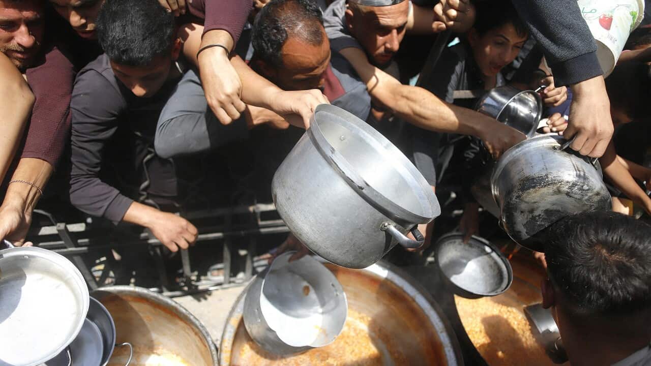 Palestinians wait to receive free food from a distribution centre in Beit Lahia, northern Gaza Strip