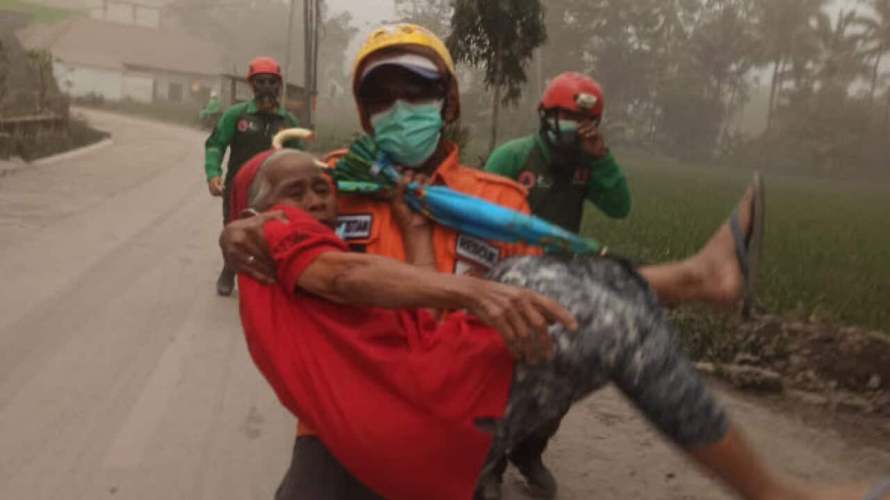 A rescue worker carrying an elderly woman
