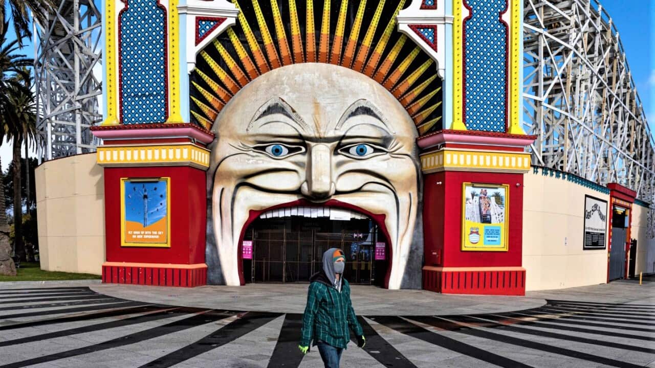 A man wearing a mask walks past Luna Park in the suburb of St Kilda during lockdown in Melbourne, Australia.