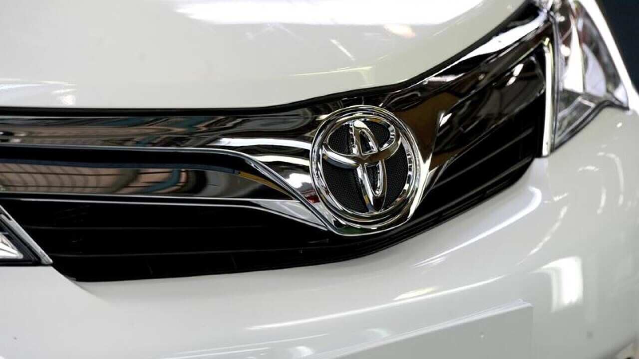 The front of a Toyota car is seen in a factory.