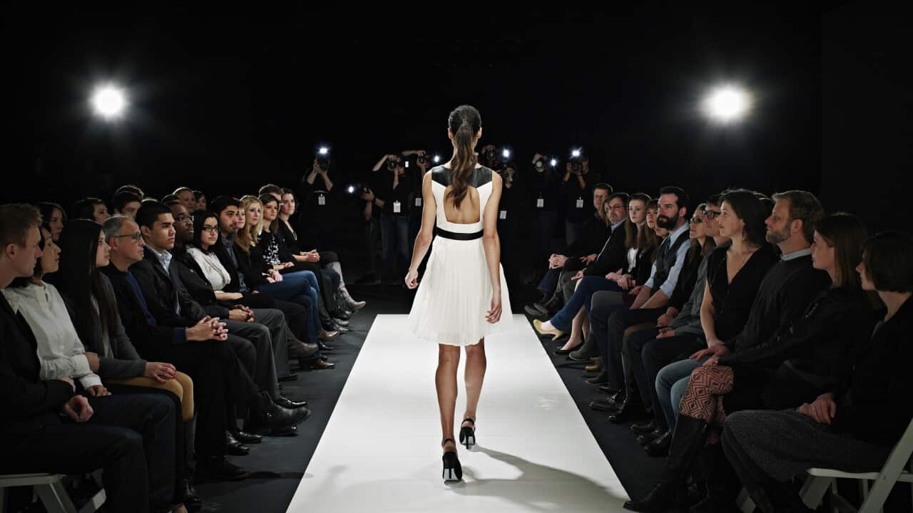 Model walking down catwalk during fashion show