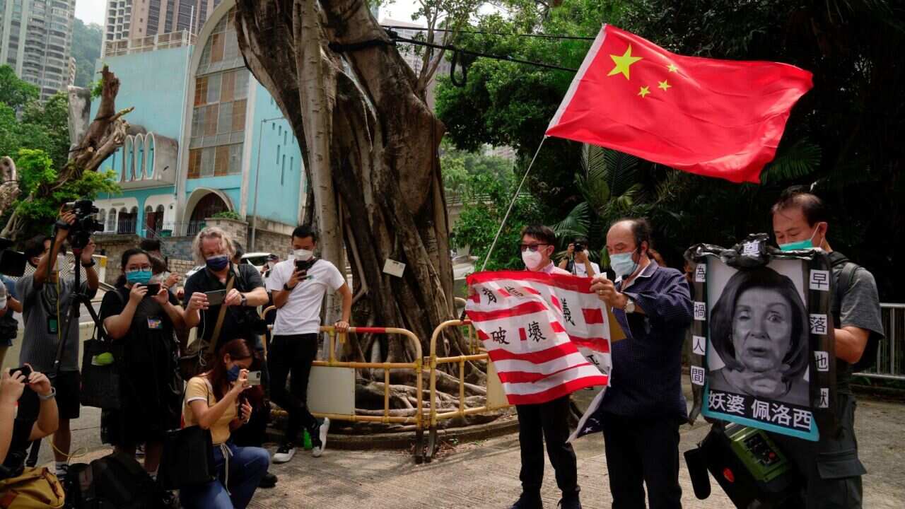 Pro-China supporters hold U.S. flag and a picture of U.S. House Speaker Nancy Pelosi during a protest outside the Consulate General of the United States in Hong Kong, Wednesday, Aug. 3, 2022.