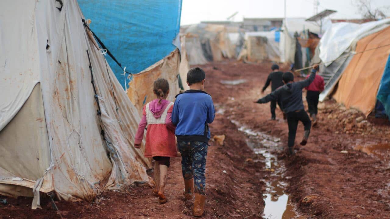 Children walking on dirty street with tents