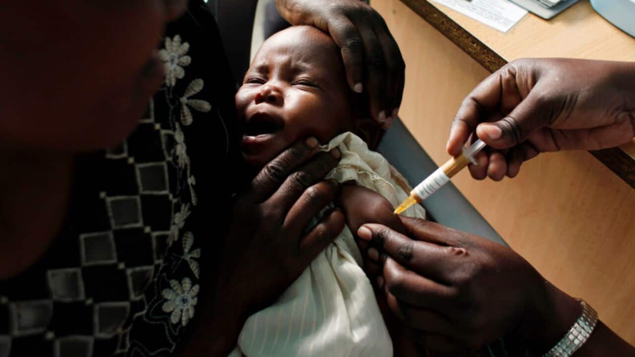 A mother holds her baby as she receives a new malaria vaccine