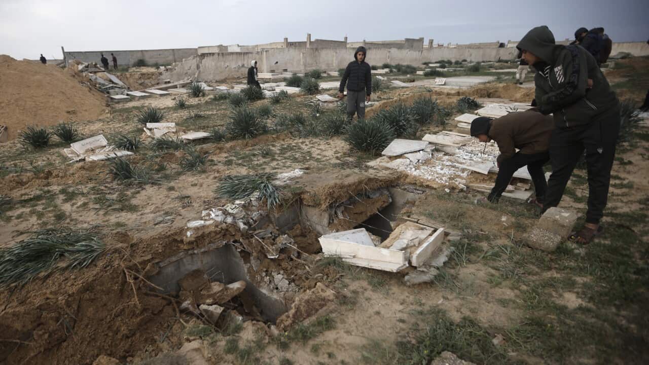 People look at the rubble of a destroyed cemetery.