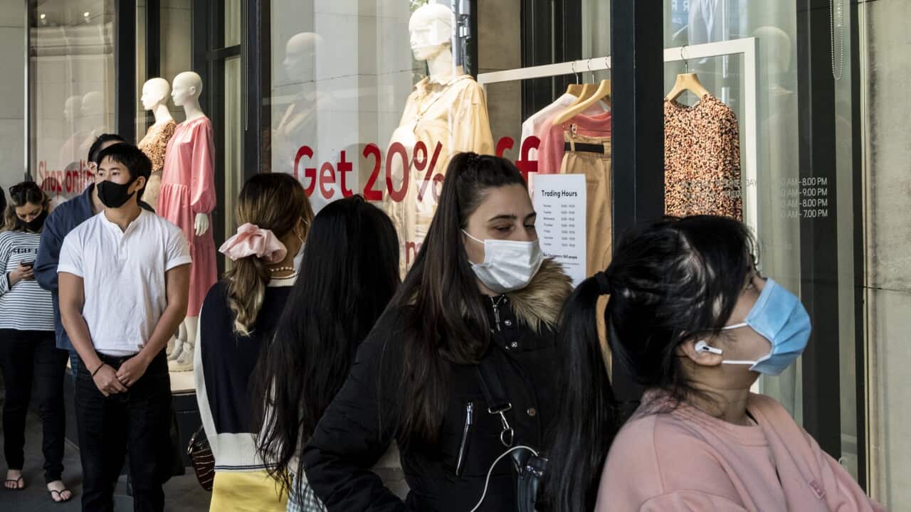 Shoppers in Melbourne wearing face masks as a preventive measure queue at the entrance of H&M for the end of season sale.