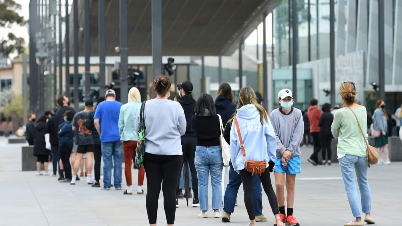 People are seen waiting in line at the Melbourne Museum for a COVID-19 vaccine.