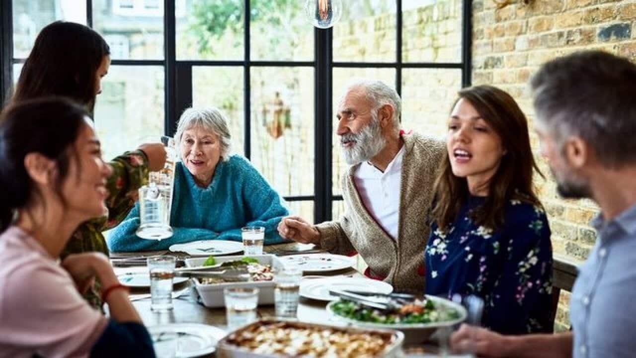 Extended family sitting round dinner table