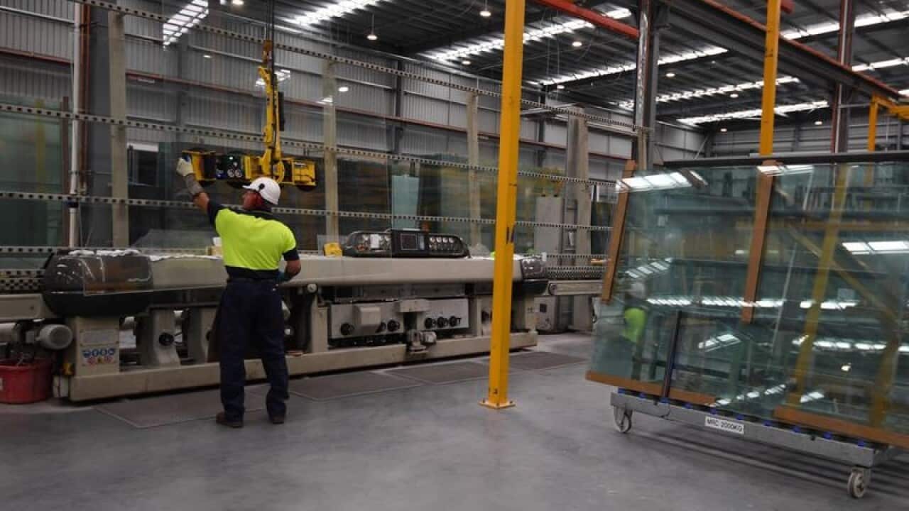 A worker is seen handling a sheet of glass at CSR Viridian in Canberra