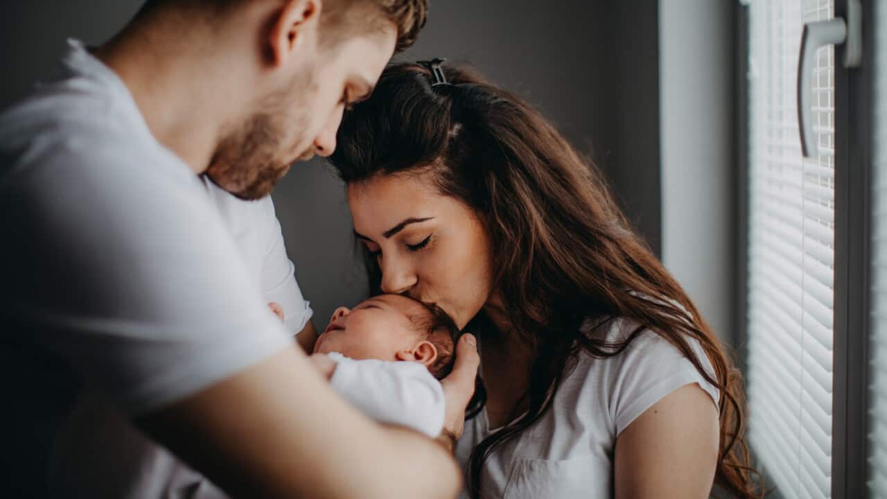 Smiling young parents with their baby girl at home