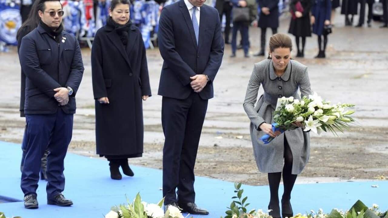 Kate lays the flowers watched by William and Vichai's family