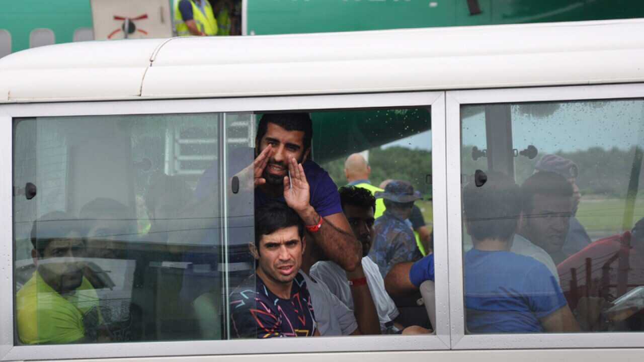 An asylum seeker calls out to journalists on Manus Island