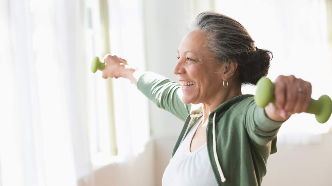 Older woman lifting weights in living room