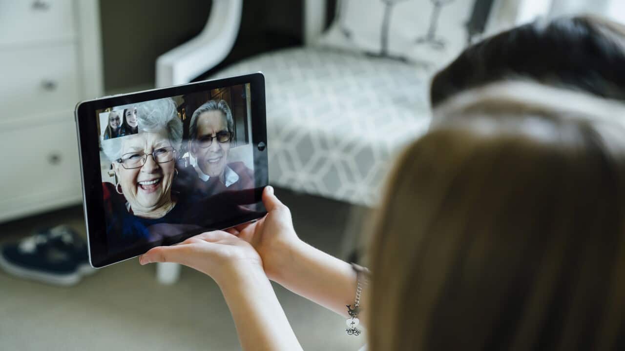 Sisters video conferencing with grandparents through tablet computer at home