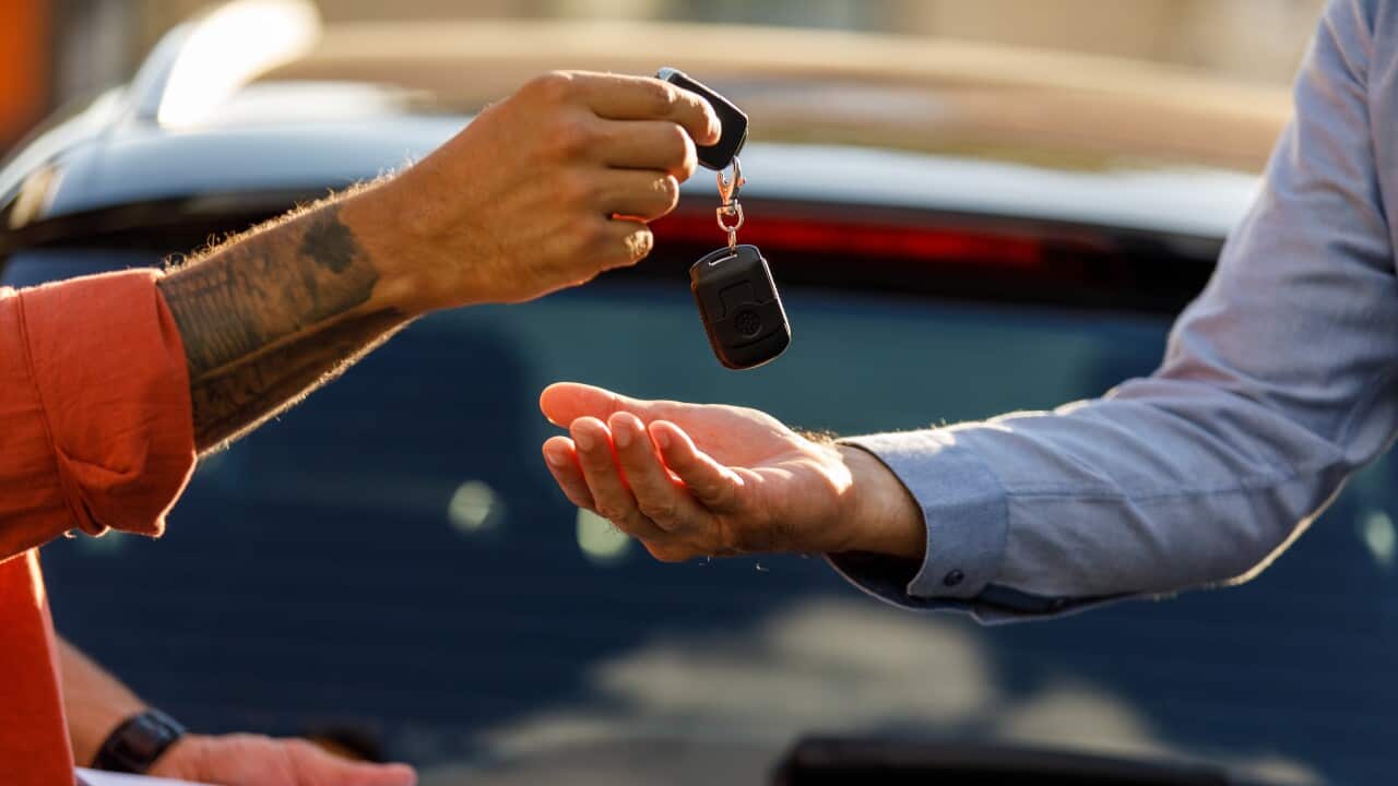 Car salesman giving the keys to the new car to a customer