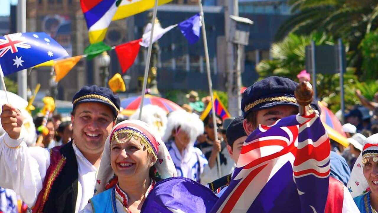 Members of Melbourne's Greek community seen marching with flags and traditional costumes